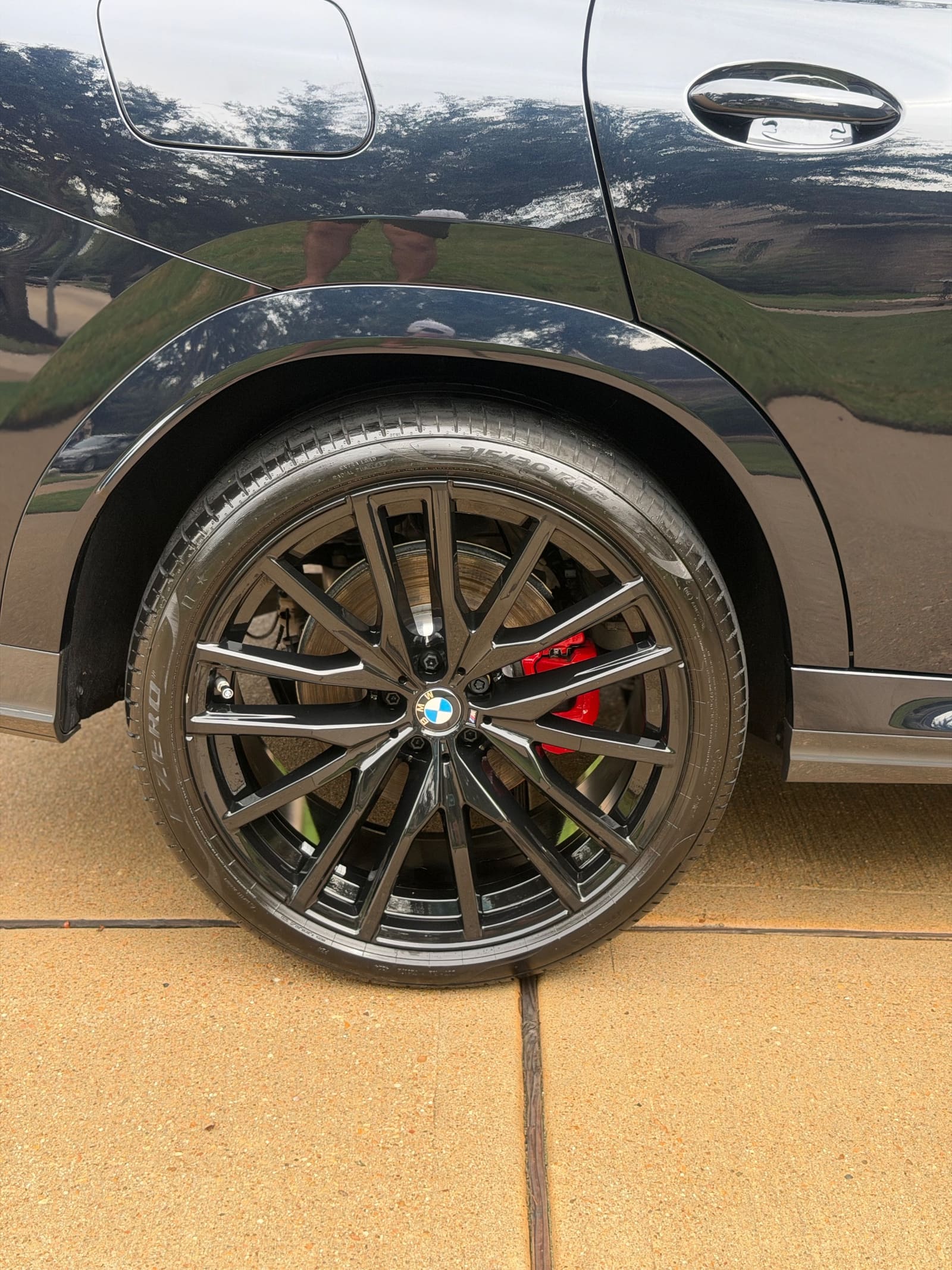 Polished wheel and wheel well of a black BMW, close up