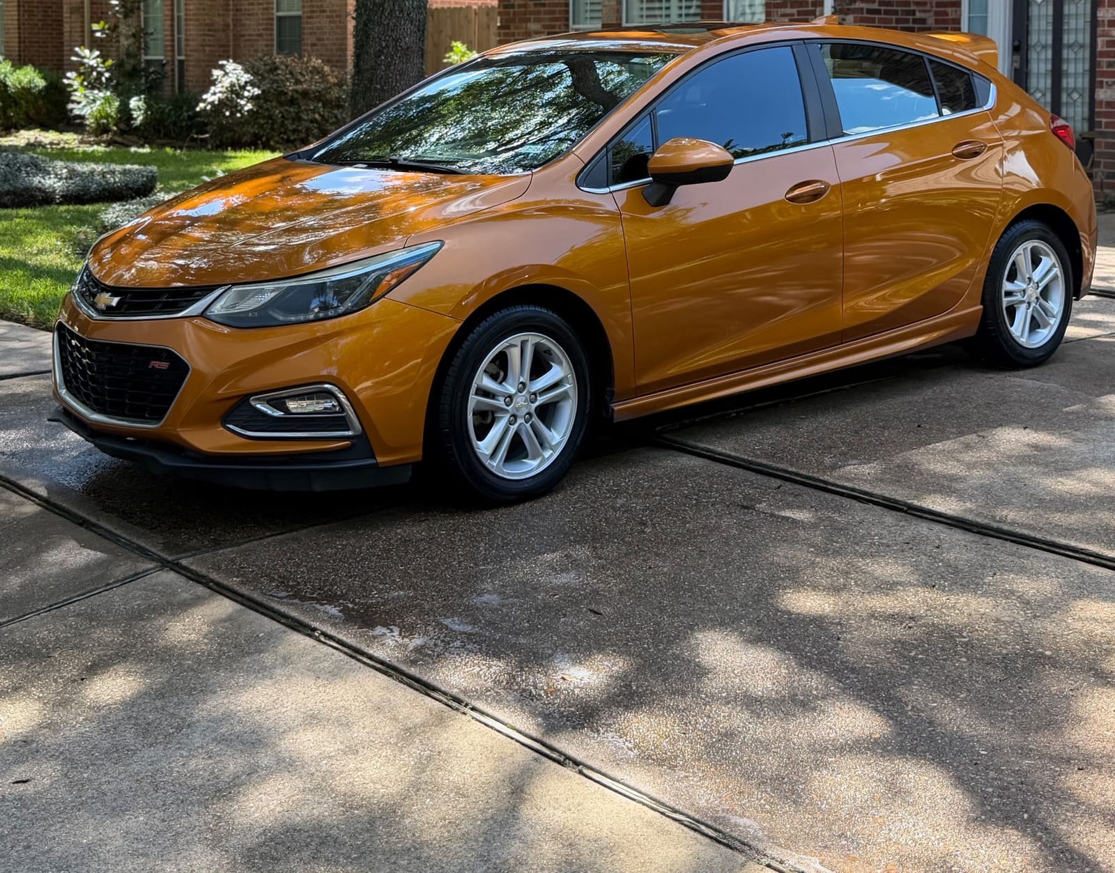 Orange Chevrolet Cruze hatchback on a driveway after a detail
