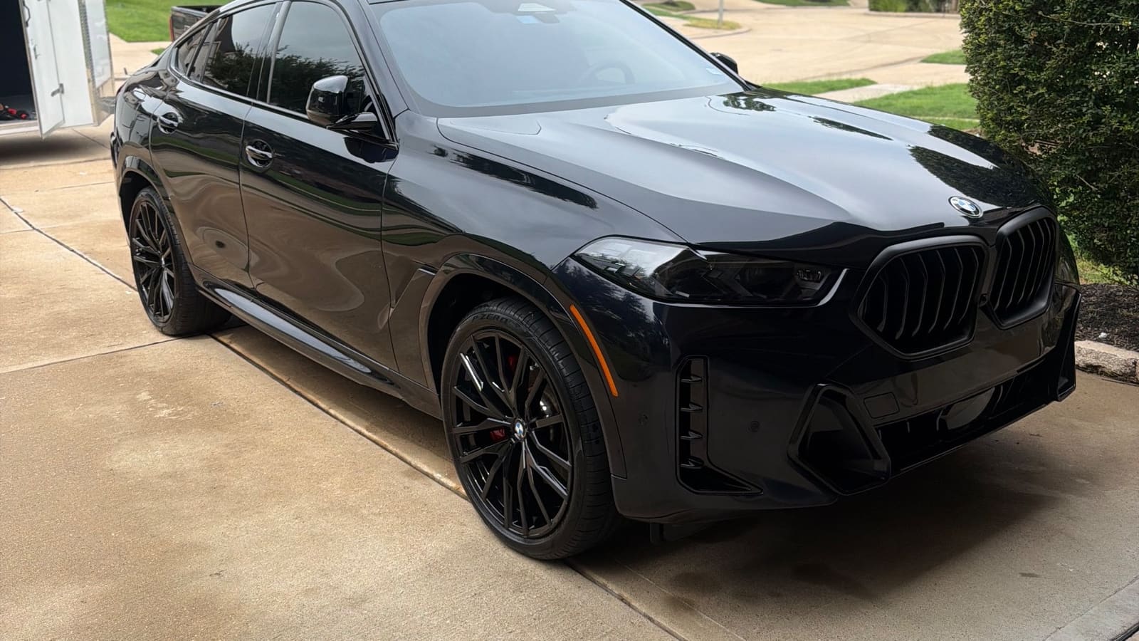 Black BMW X6 on a driveway, the front polished to a mirror finish