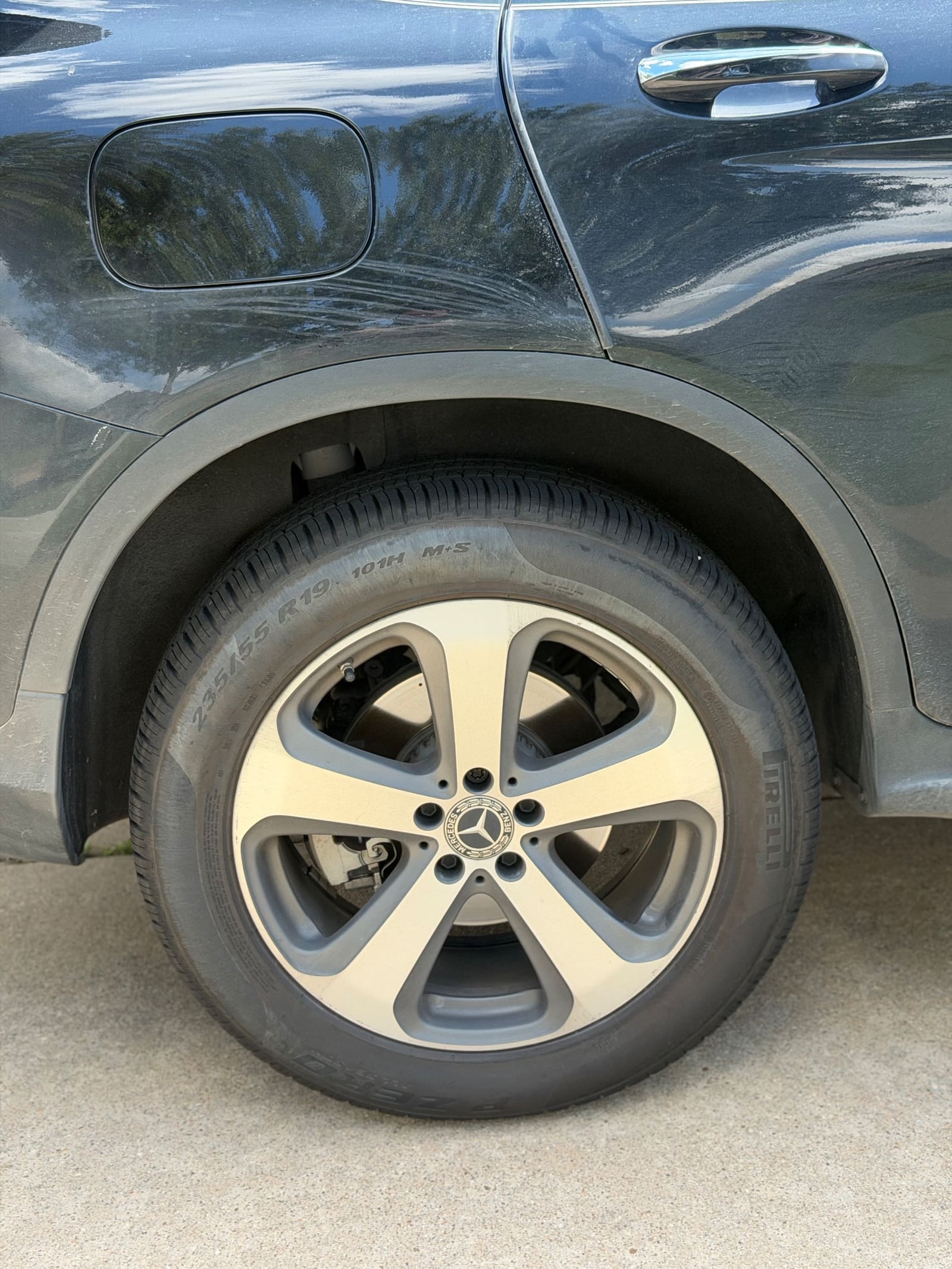 Dull black Mercedes flank and dusty wheel before a detail